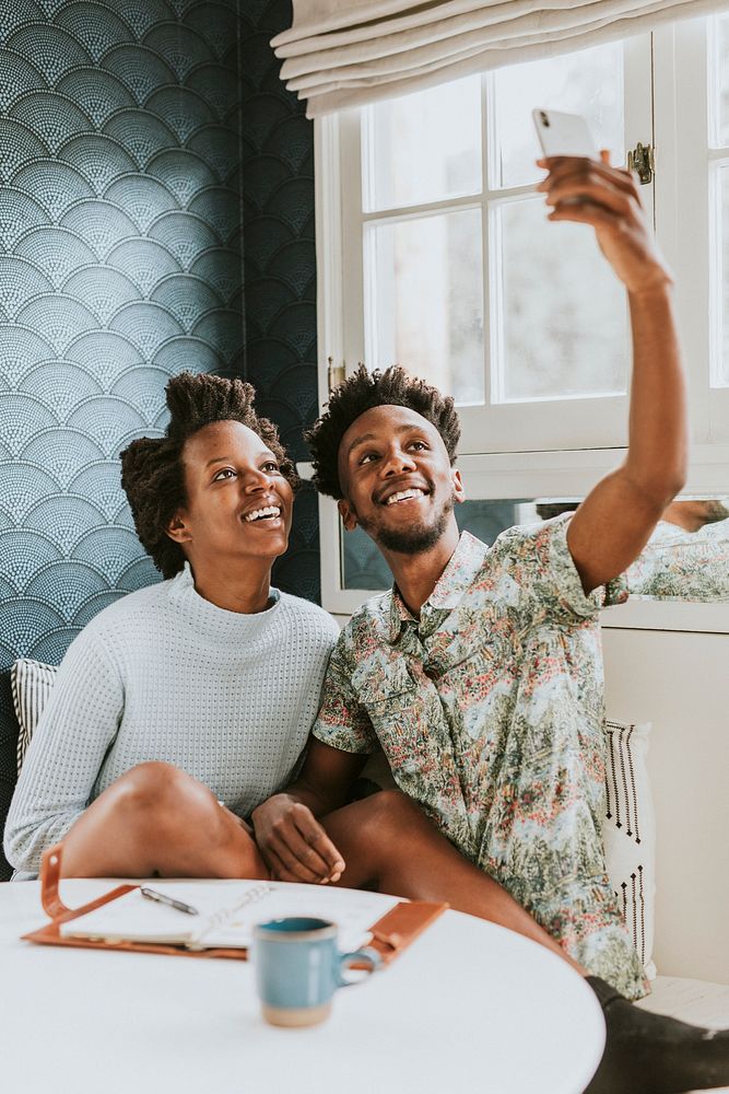 Happy black couple taking a selfie at home with a mobile