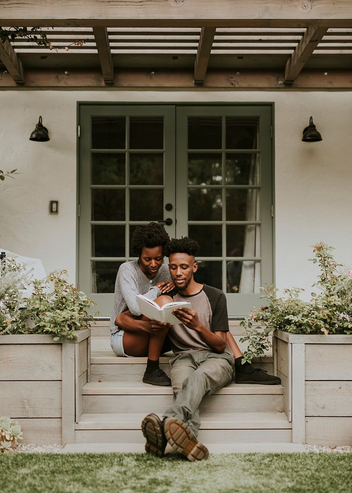 Cute black couple reading a book together in a garden
