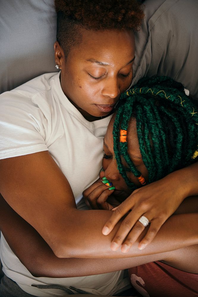 Cuddling lesbian couple asleep in bed