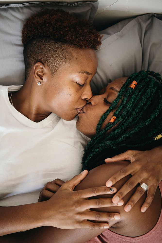 Happy lesbian lovers kissing in bed