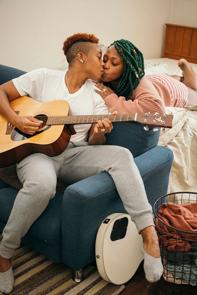 Happy lesbian couple with a guitar kissing