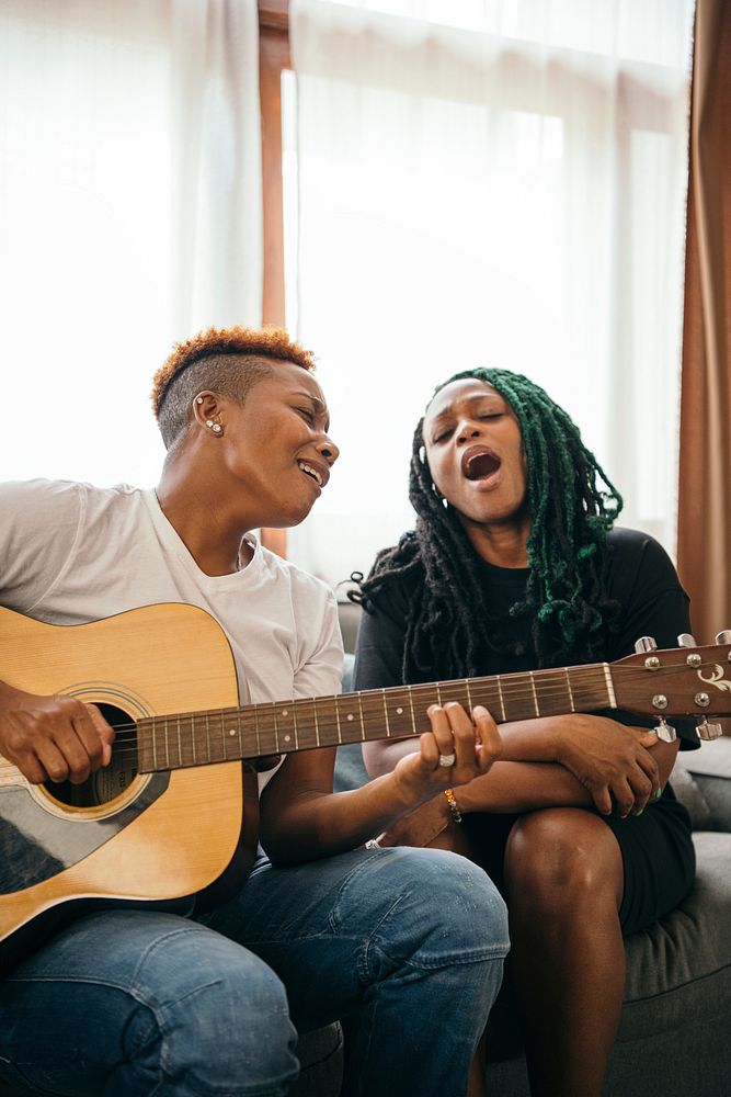 Happy lesbian couple playing the guitar and singing