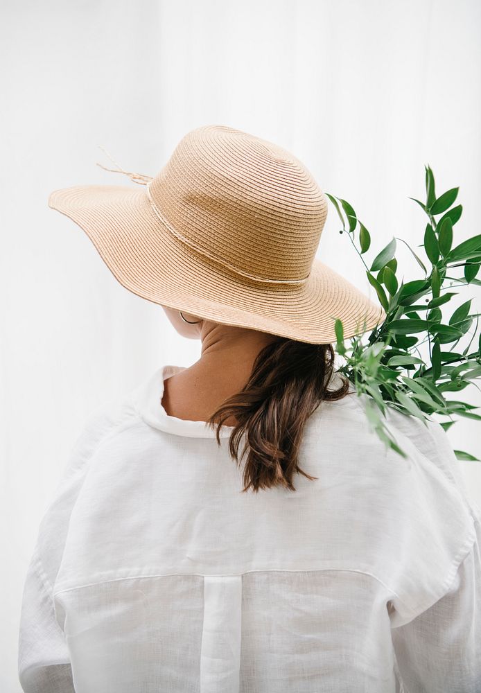 Woman wearing a woven hat carrying eucalyptus leaves