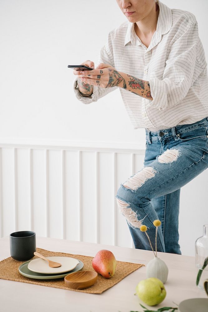 Tattooed woman taking a photo of the minimal dish set