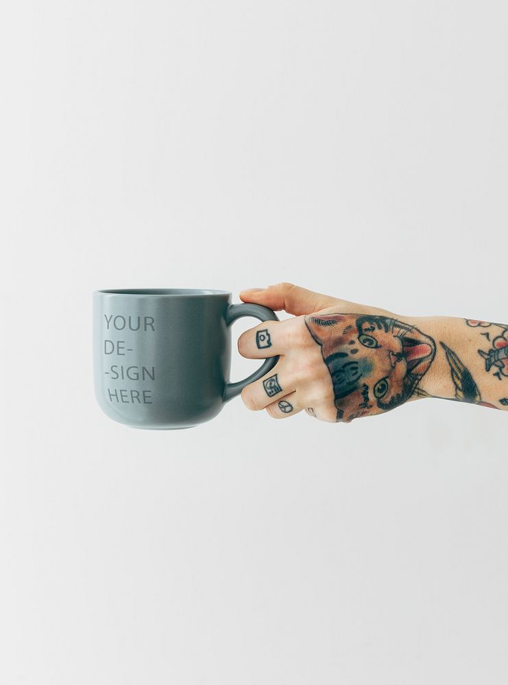Tattooed hand holding a grayish blue coffee cup mockup
