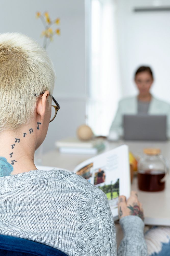 Blonde woman with tattoo reading a book
