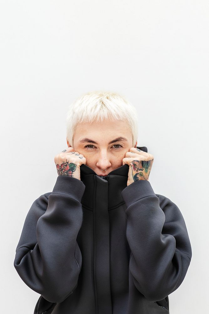 Tattooed woman covering her face with a black hoodie