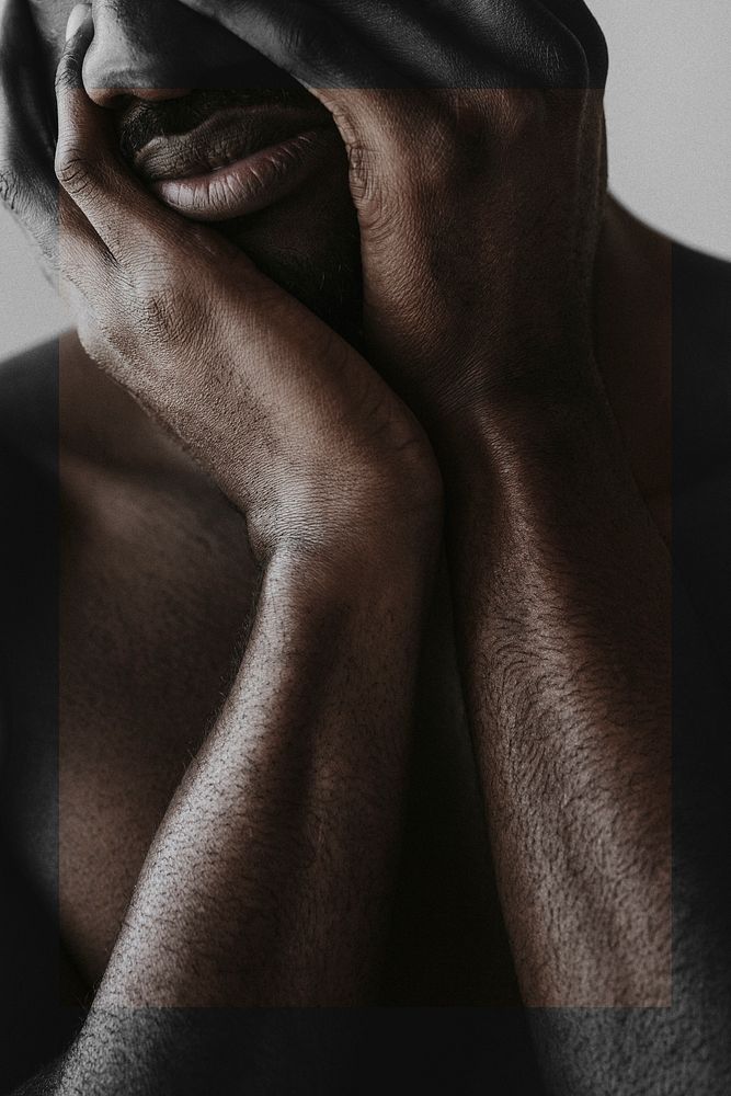Stressed black man covering his face with hands