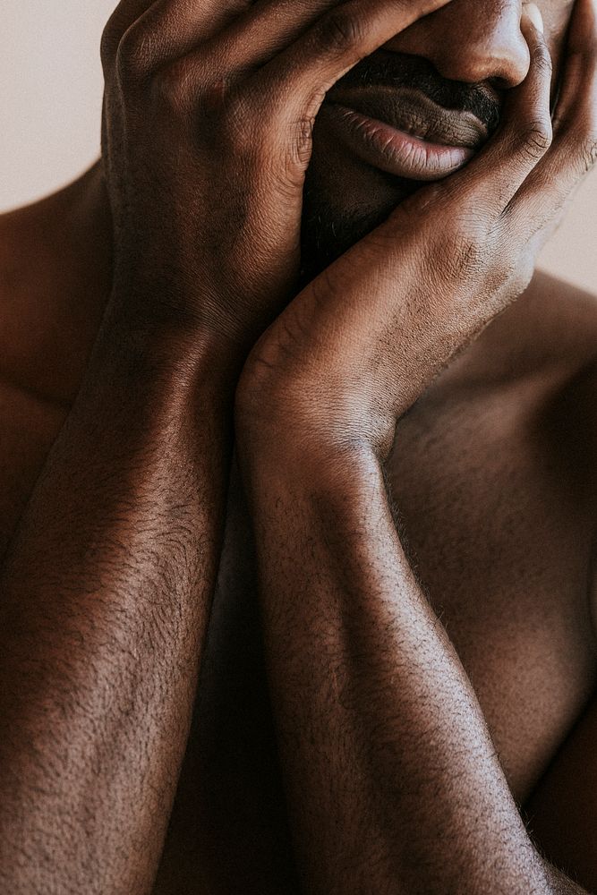 Stressed black man covering his face with hands