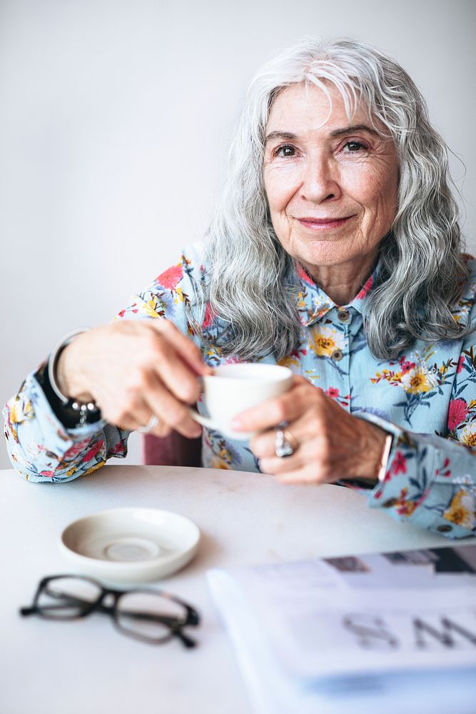 Cheerful grandmother sipping coffee in a cafe