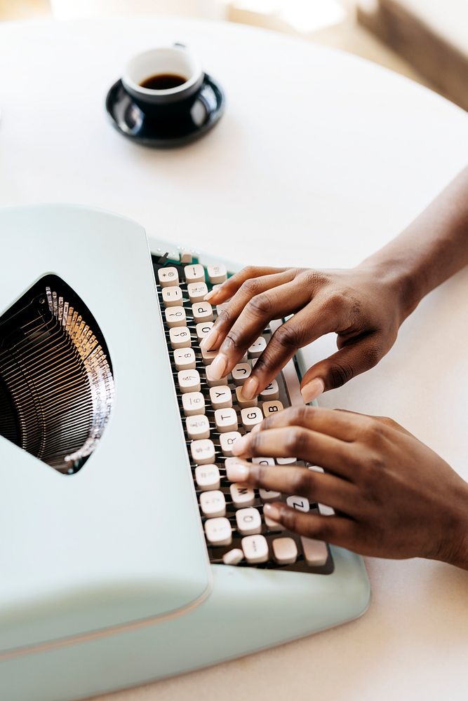 Hands typing on retro light blue pastel typewriter