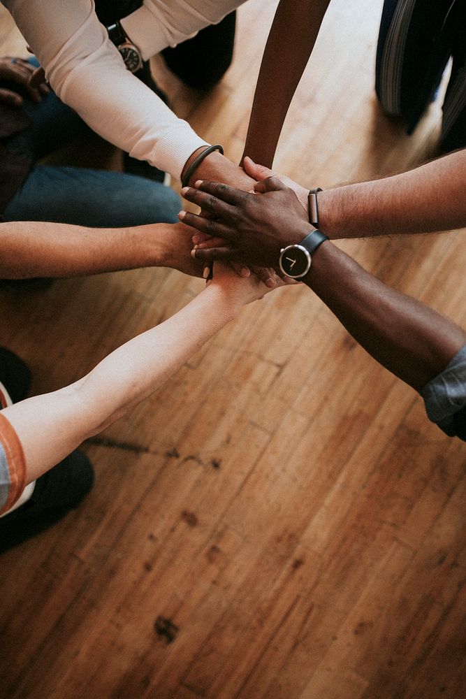 Diverse people joining hands in the middle
