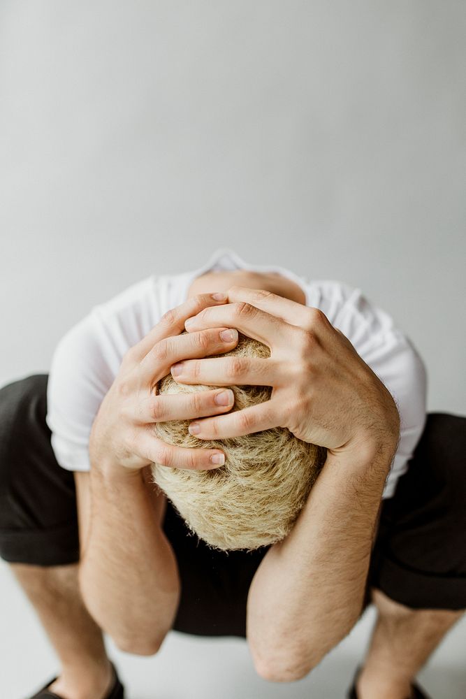 Depressed man covers his head with hands