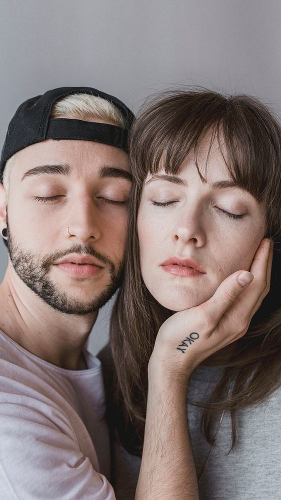 Man touching eyes-closed woman face