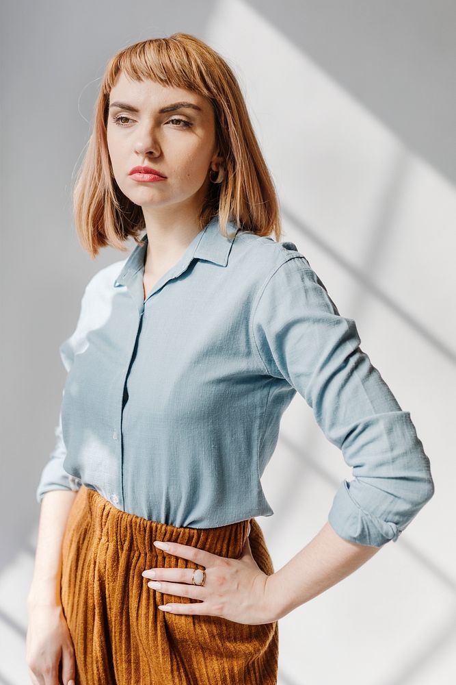 Woman in a blue shirt by the white wall