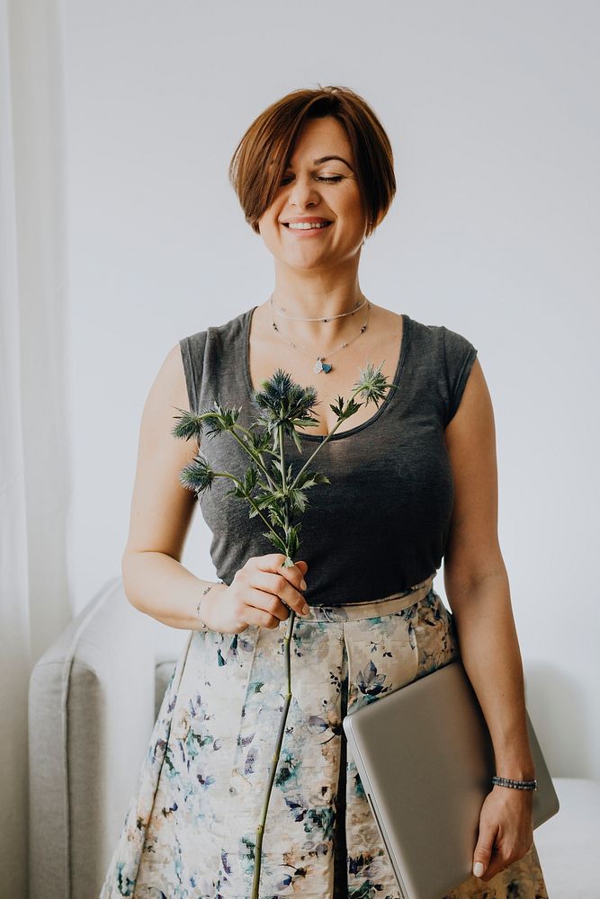 Cheerful woman holding a blue thistle and a laptop