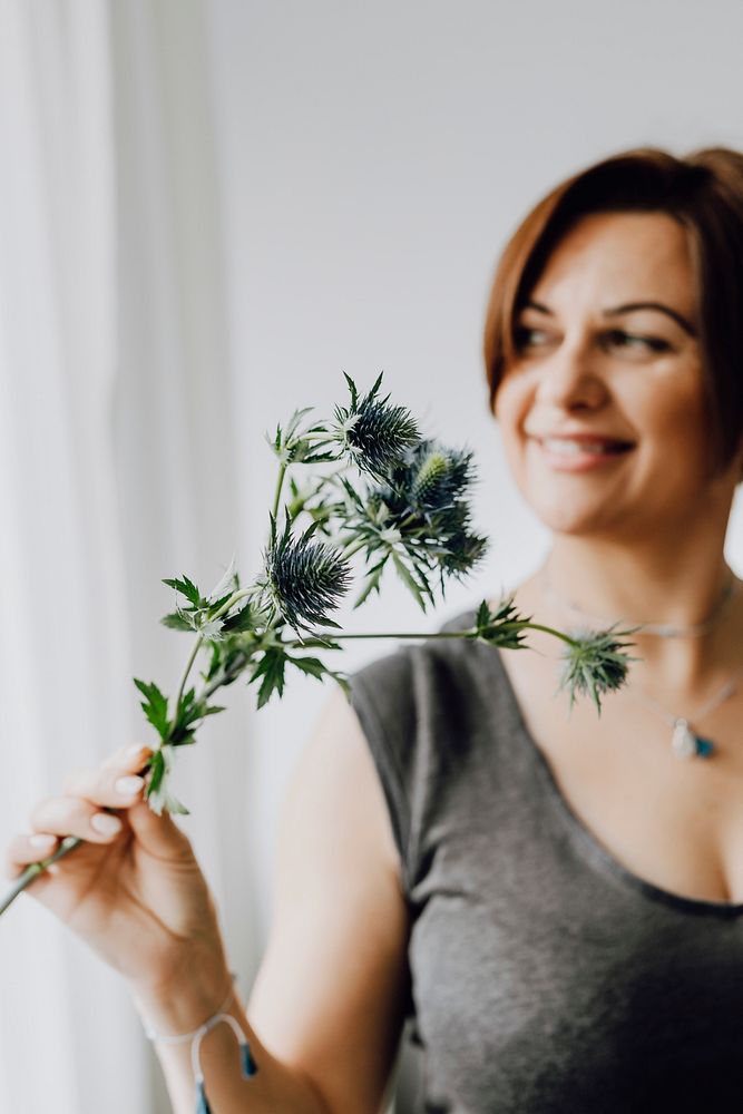 Cheerful woman holding a blue thistle