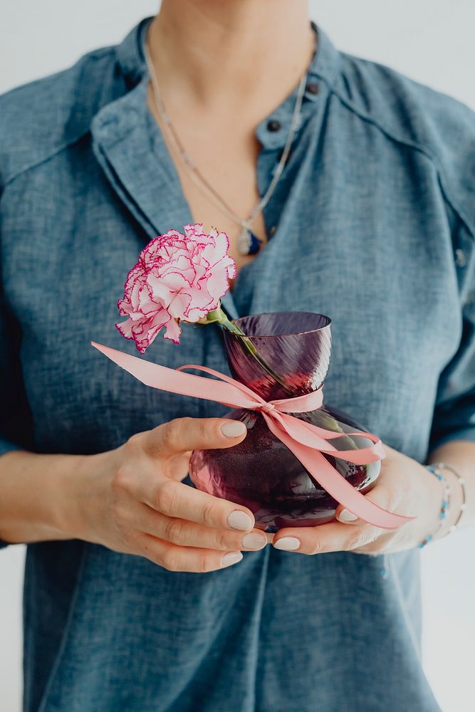 Woman holding a vase of a white pink carnation