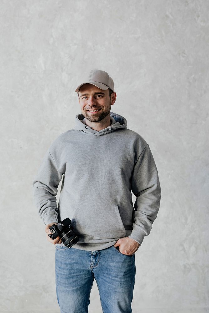 Spy wearing a cap and a hoodie holding a camera