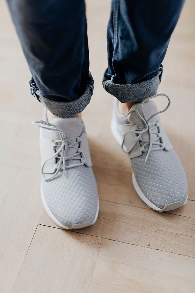 Woman in gray sneakers standing on a wooden floor