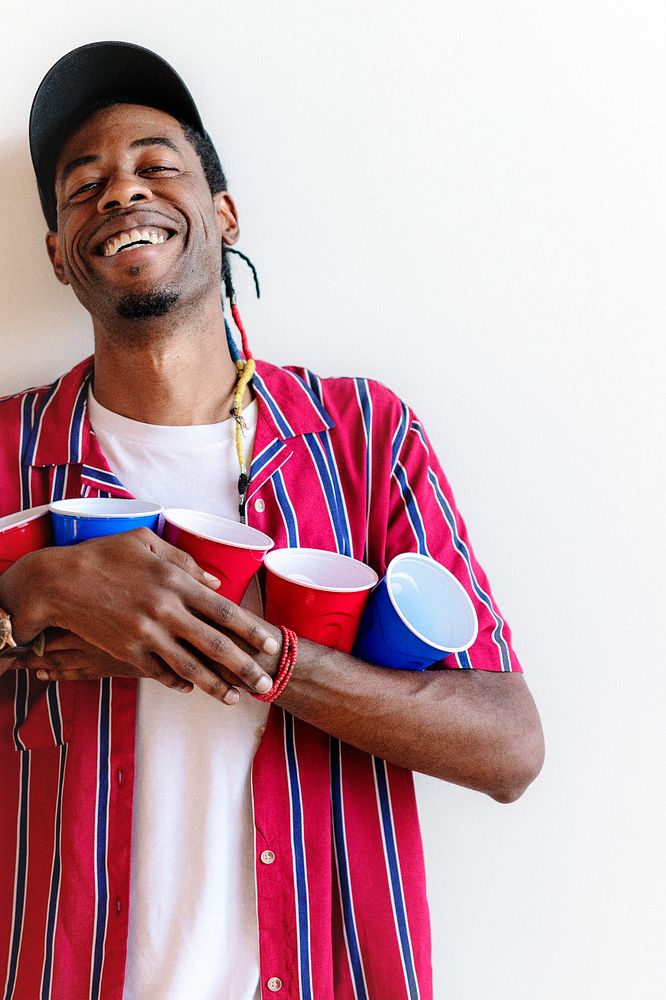 Cheerful young man holding red and blue cups