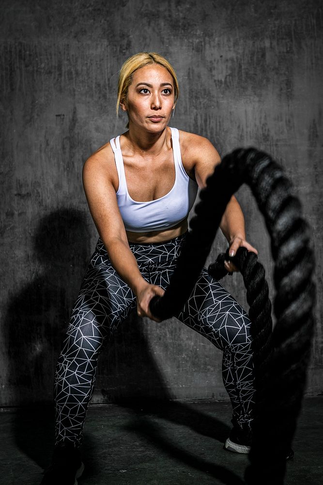 Sportive woman working out on the battle ropes