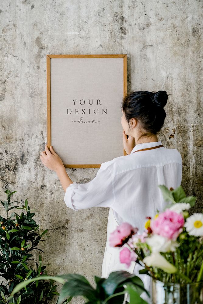Woman putting up a frame mockup on a grungy wall