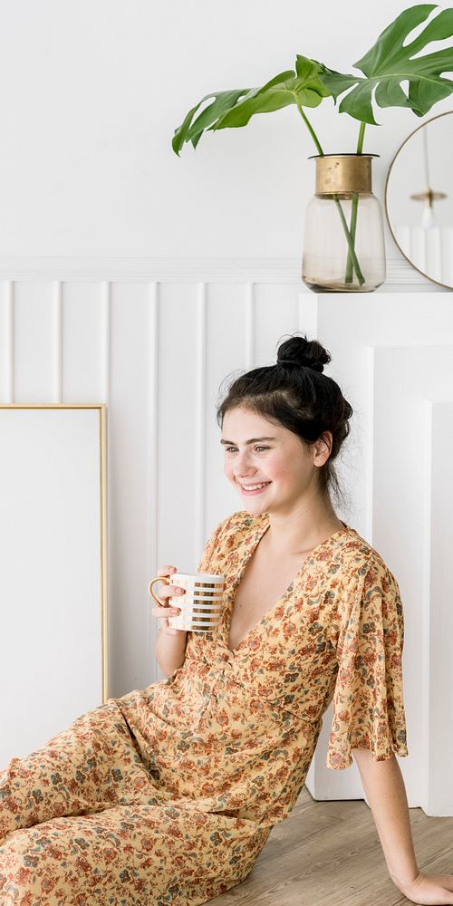 Cute happy girl with a coffee mug sitting by a frame