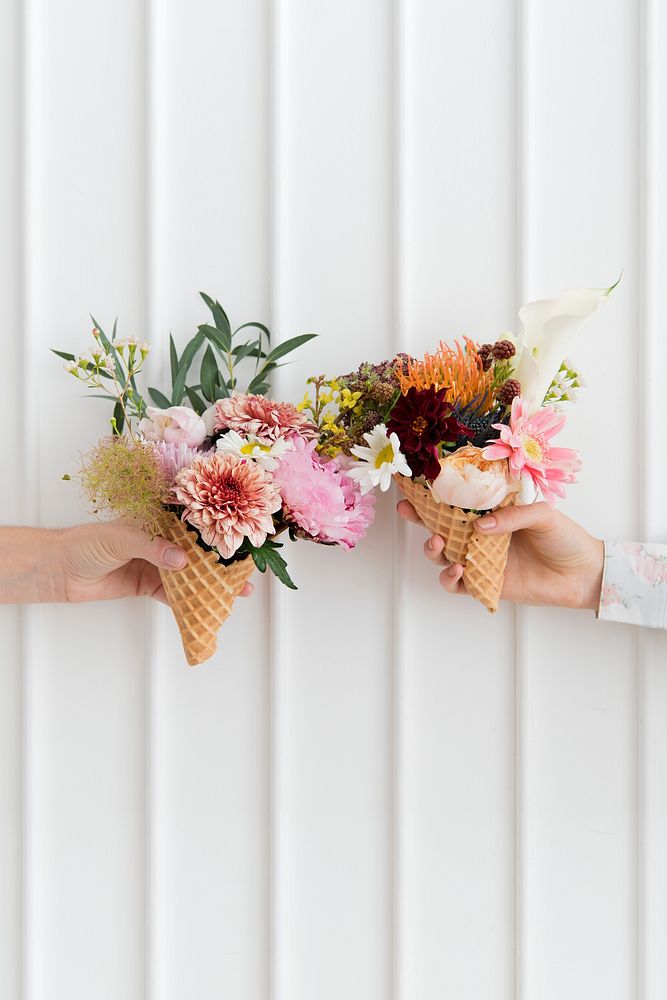 Two women holding up flowers in ice cream cones