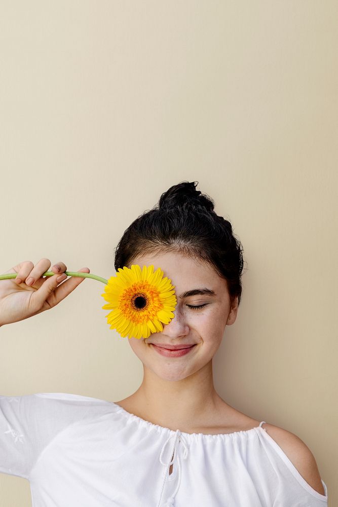 Beautiful young girl with a yellow gerbera flower