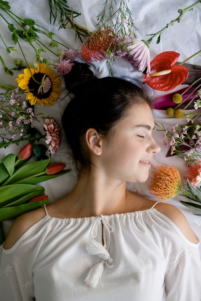 Beautiful young girl lying in a bed with flowers