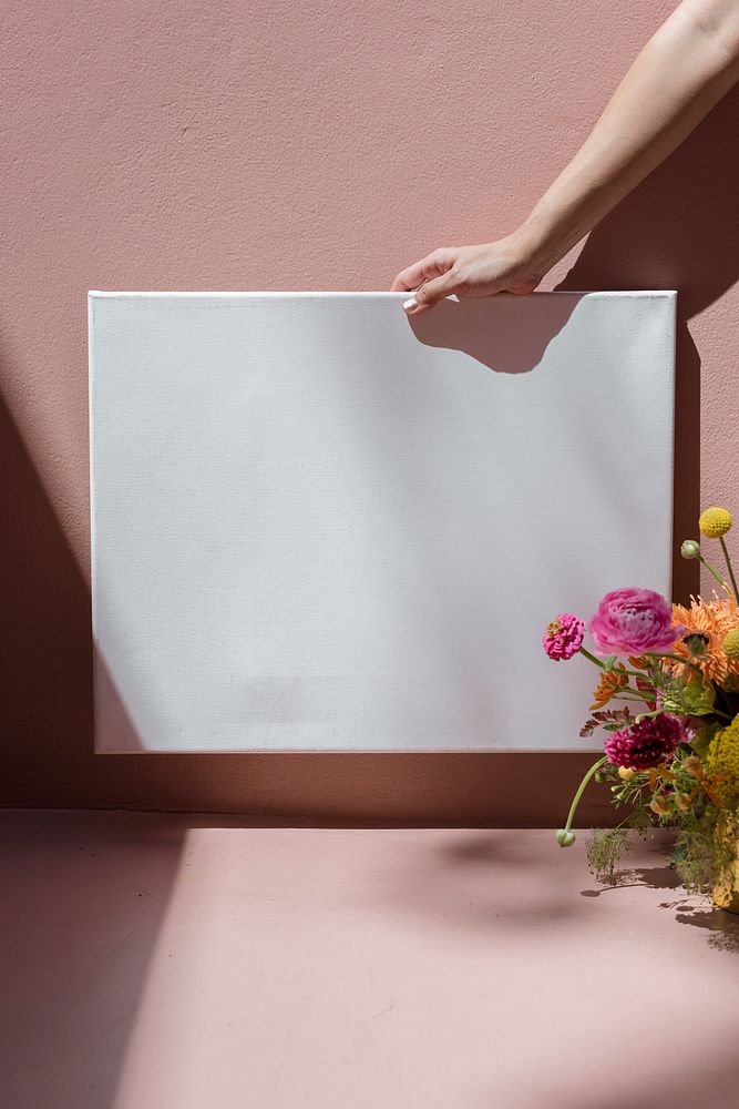 Woman holding a blank frame mockup against a pink wall