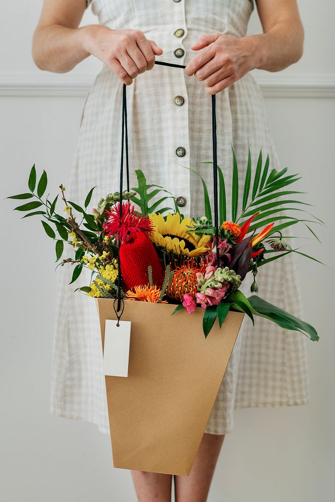 Woman carrying a tropical bouquet in a shopping bag