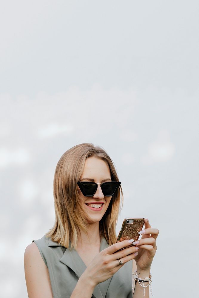 Happy woman playing on her phone outdoors