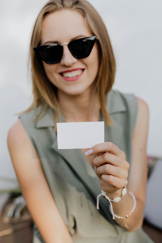 Friendly woman in sunglasses carrying a business card mockup
