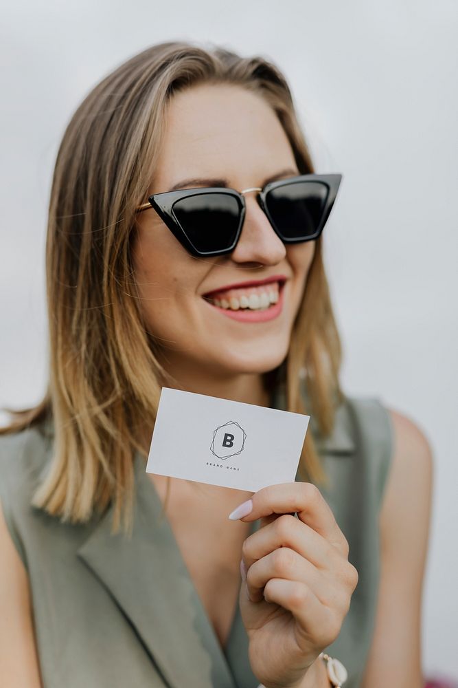 Friendly woman in sunglasses carrying a business card mockup