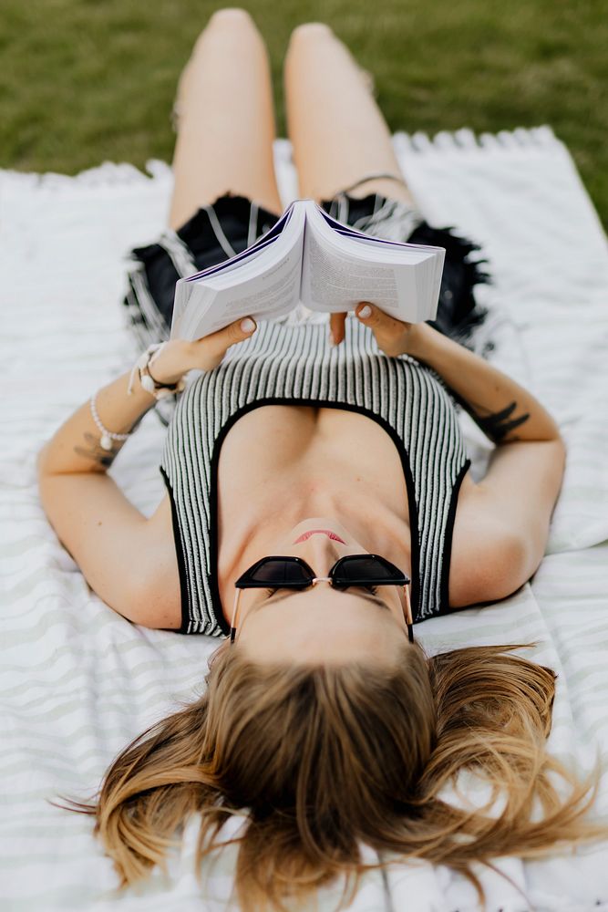 Woman laying on the grass reading a book