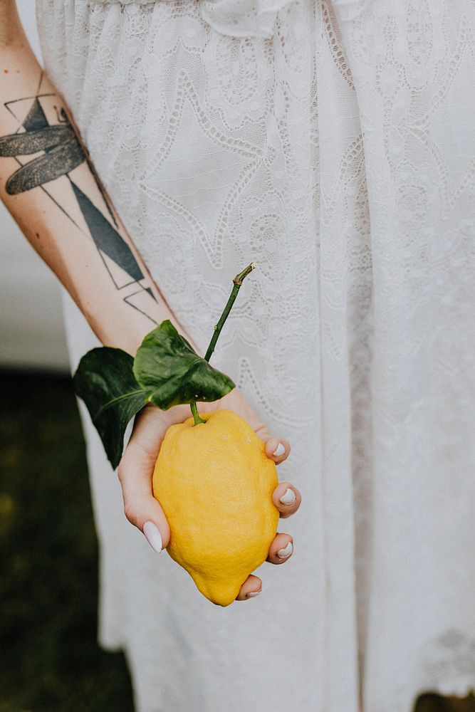Tattooed arm holding a fresh lemon