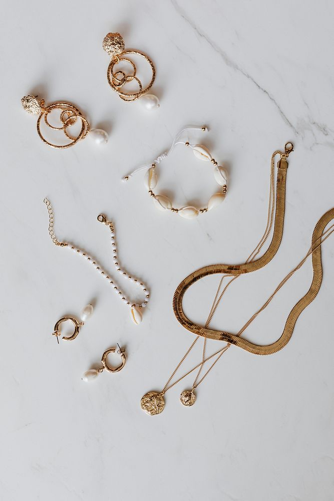 Aerial view of gold jewelries on a white marble background