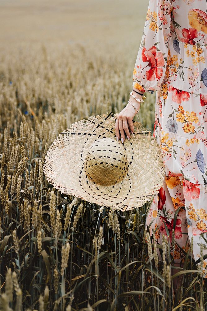 Woman in a floral dress with a woven hat in a field