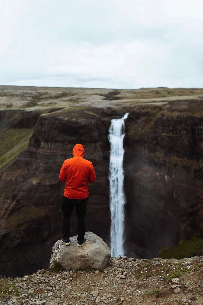 Man in a red windbreaker at the Haifoss waterfall, Iceland