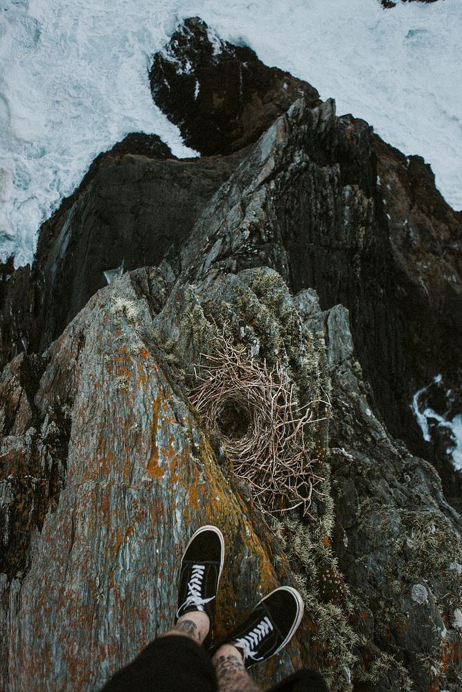 Tattooed man standing on a cliff by the beach