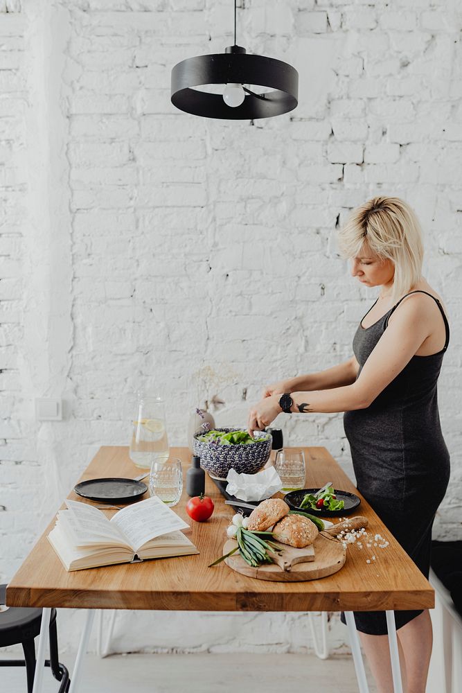 Expecting mother eating salad in the kitchen