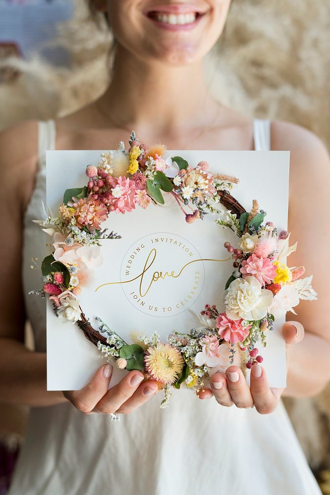 Bride holding a flower wreath with a wedding invitation