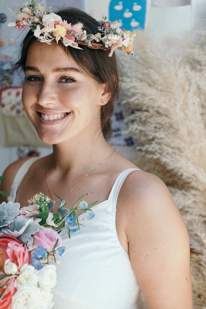 Smiling woman wearing a flower wreath and holding a bouquet of assorted flowers