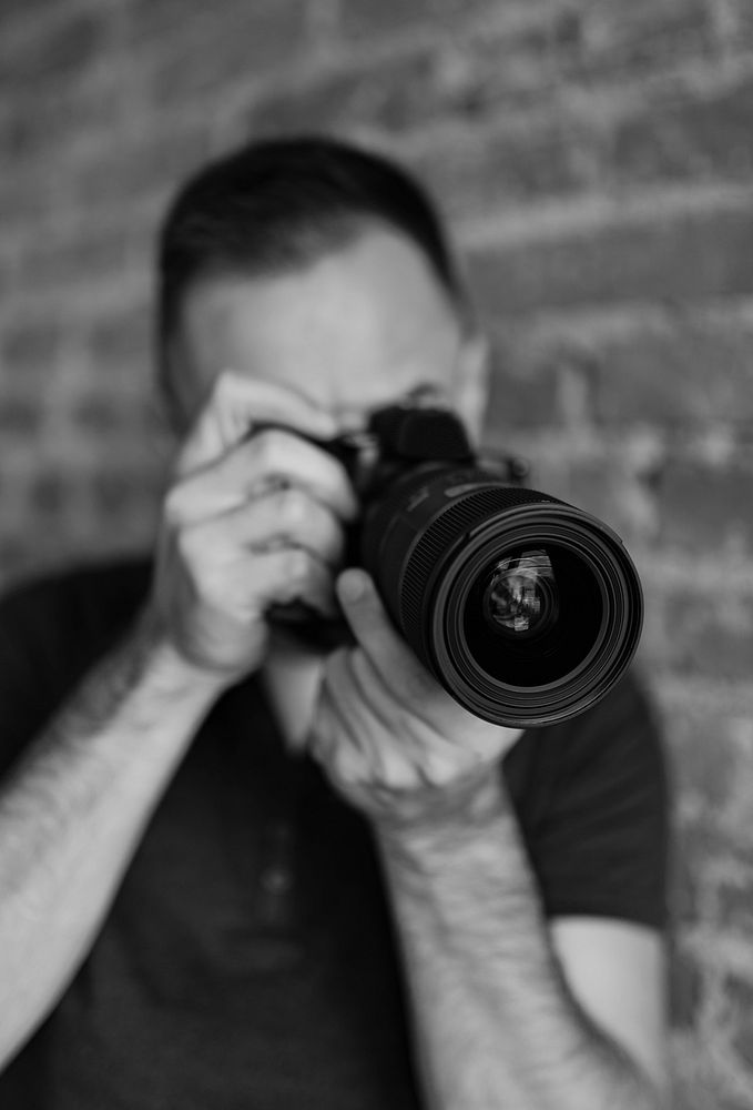 Male photographer taking a photo with his DSLR camera grayscale