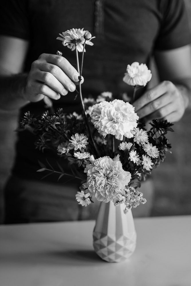 Man arranging flowers in a vase grayscale