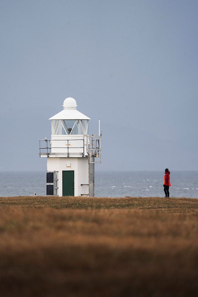Female traveler at Vaternish Lighthouse on Isle of Skye, Scotland