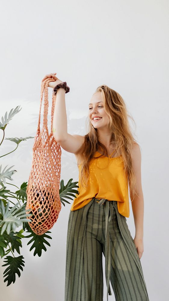 Blond girl holding a net bag with vegetables inside mobile phone wallpaper