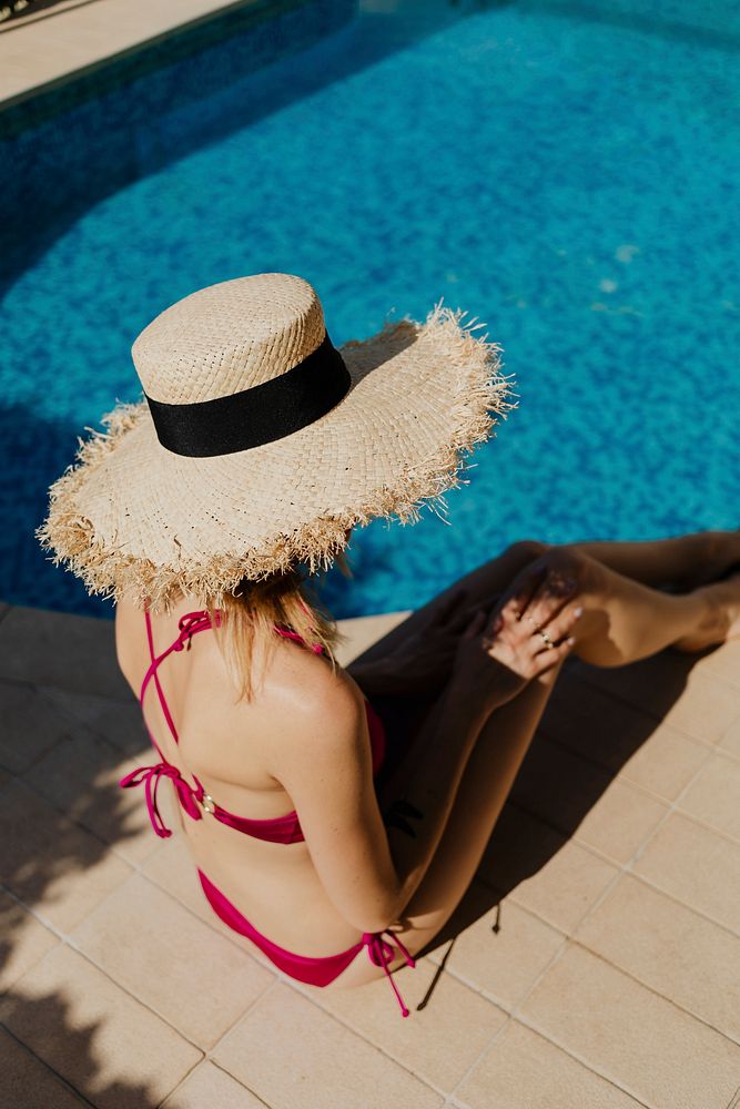 Woman in a pink bikini sitting by the pool